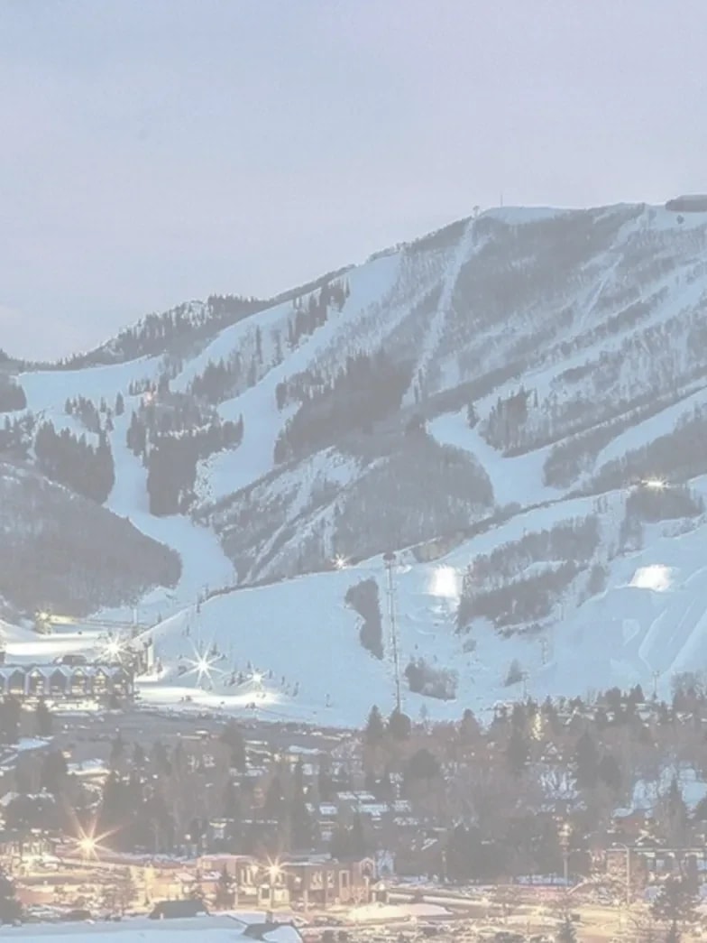 Park City ski slopes lit at dusk above the town lights